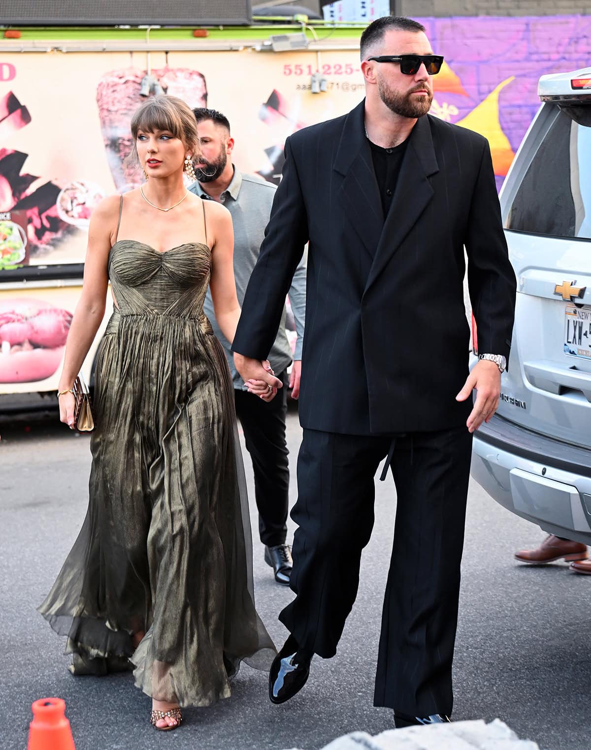 Taylor Swift and fiancé Travis Kelce look dazzling in a Maria Lucia Hohan dress with Aquazzura heels and a Fear of God striped blazer with patent boots on their way to a friend's wedding in Brooklyn on Sunday