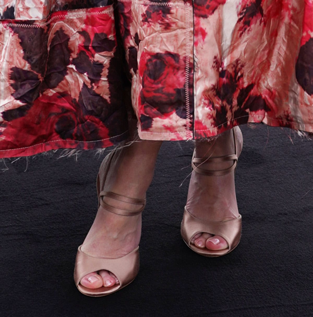Emily Blunt slips into a pair of metallic champagne sandals with peep toes, two slim straps across the foot, and stiletto heels