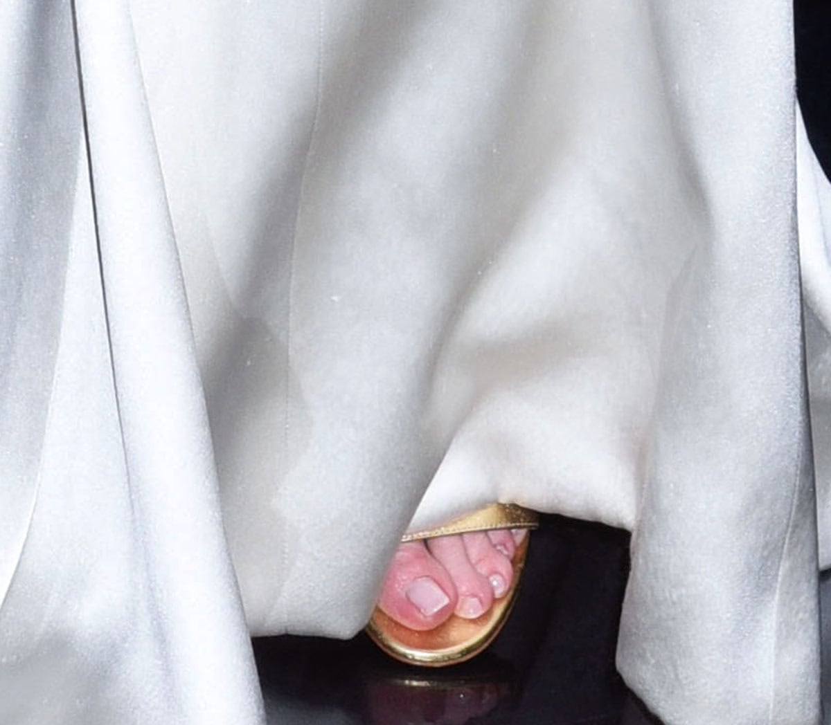 Emily Blunt slips into a pair of metallic gold sandals with open toes and a mirror-effect finish