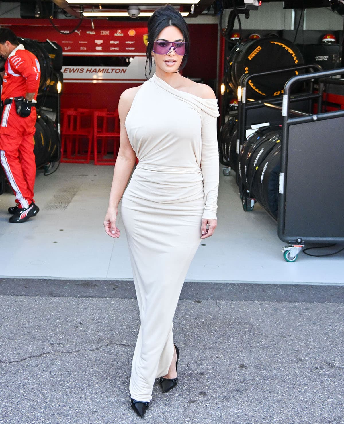 Kim Kardashian pairs her pumps with an off-white Gucci draped dress featuring an asymmetric neckline, with one side left sleeveless and the other draping off the shoulder and extending into a long sleeve
