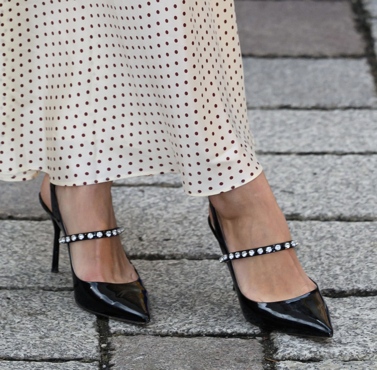 Pixie Geldof adds a touch of sparkle with glossy black Miu Miu slingback pumps, featuring crystal-embellished Mary Jane straps that contrast beautifully against her romantic polka-dot dress