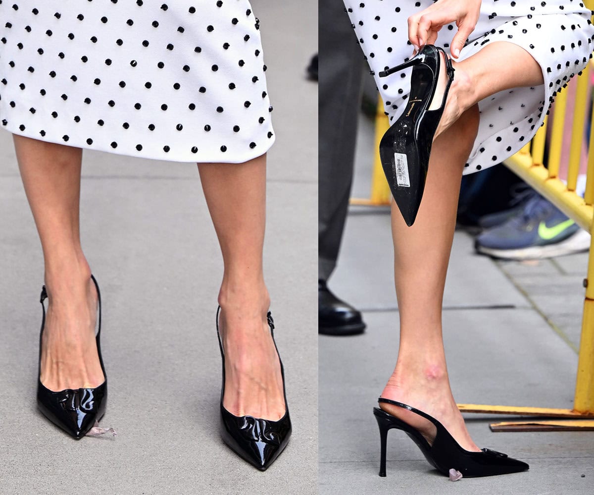 Emmy Rossum wears a pair of shiny black patent pumps with slingback straps, pointed toes with a sculptural vamp detail, and high heels