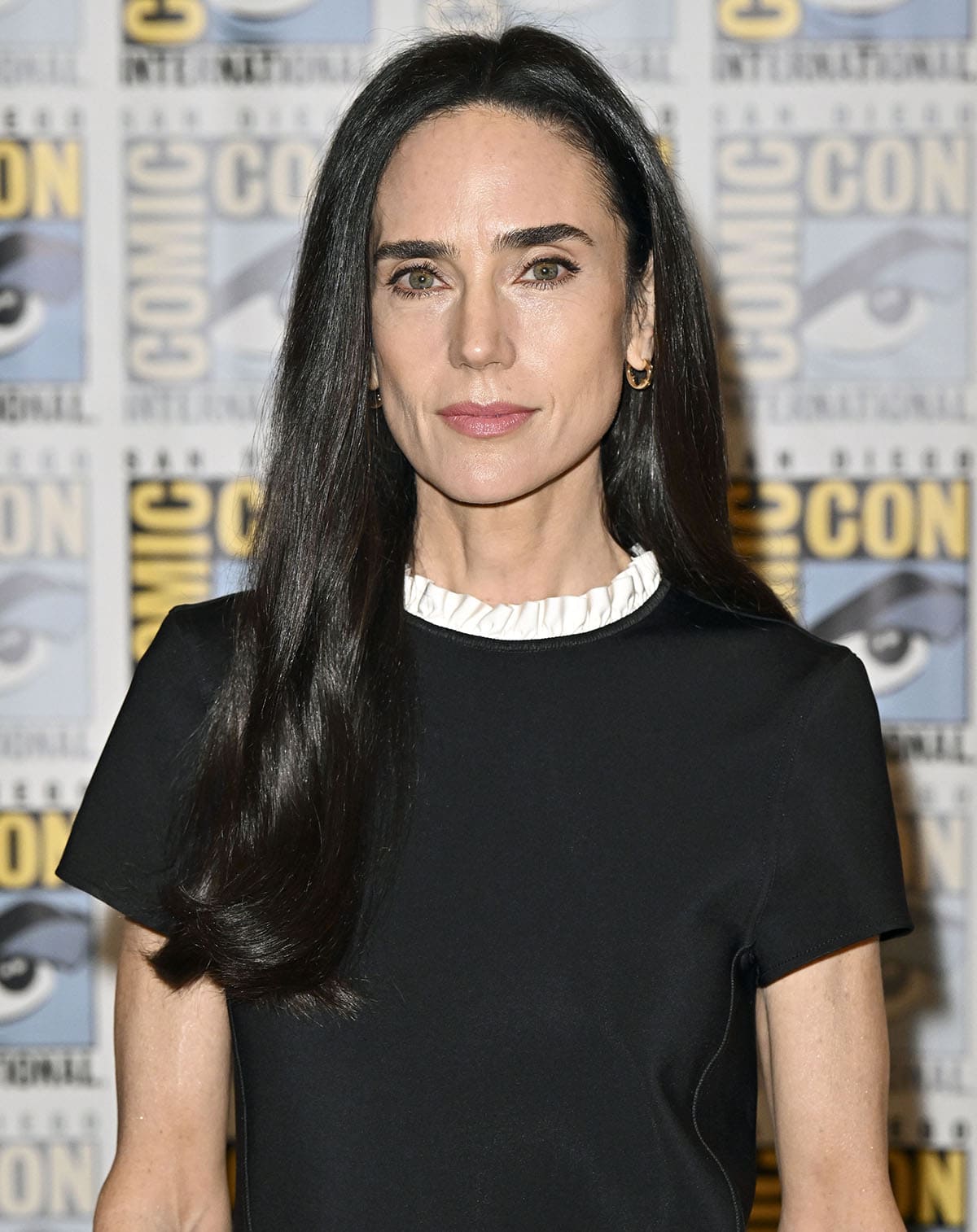 Jennifer Connelly keeps the rest of her look simple with tiny hoop earrings, soft makeup, and soft wavy hair