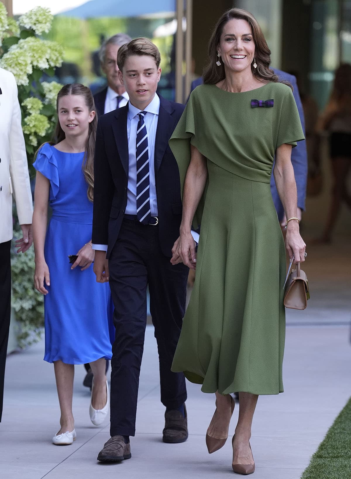 Kate Middleton pairs her brown pumps with a green Emilia Wickstead midi dress featuring an asymmetric cape-like overlay for Day 14 of the Wimbledon Tennis Championships