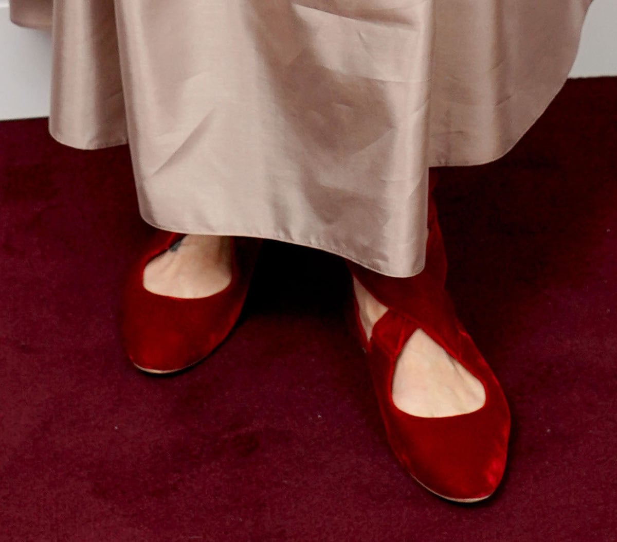 Marisa Tomei adds a pop of color to the event with her plush red velvet The Row “Elodie” flats featuring wide crisscross straps that wrap around the leg