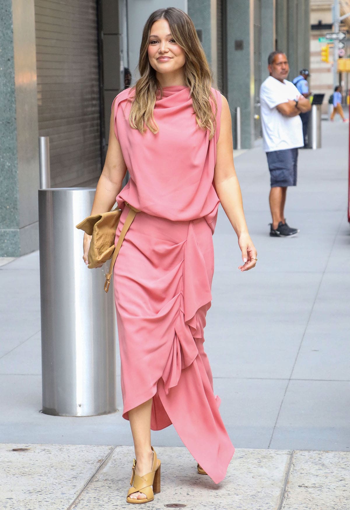 Olivia Holt pairs her summertime heels with a guava pink Michael Kors ensemble featuring a draped top and a midi skirt with cascading draped ruffles on one side