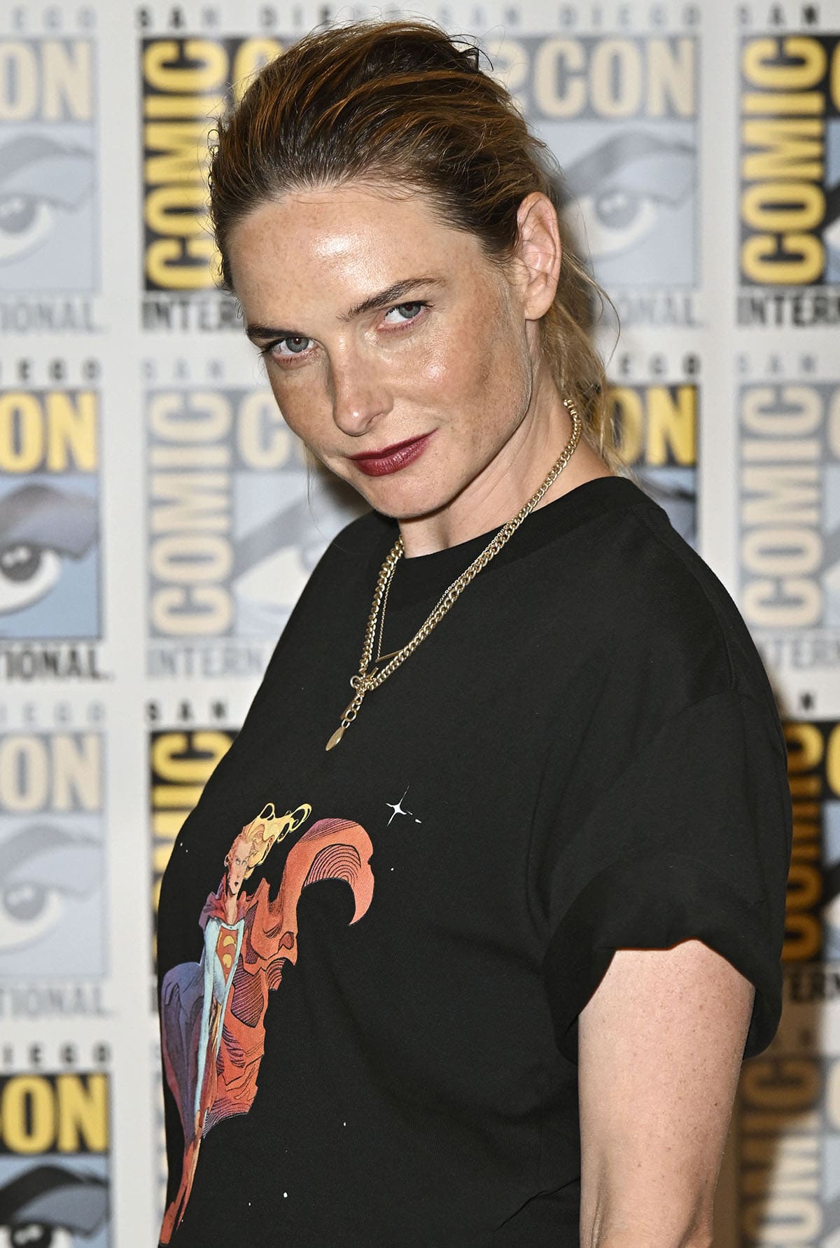 Rebecca Ferguson styles her casual look with chain necklaces, a loose ponytail, and red lipstick