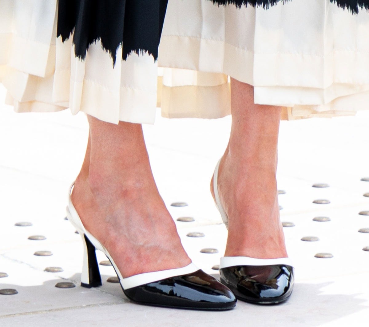 Sarah Pidgeon keeps her footwear sleek and modern, wearing a pair of two-tone Chanel pumps with shiny black cap toes, slingback straps, and flared heels