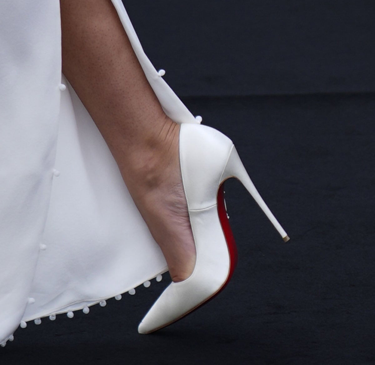 Zendaya steps into one of her signature red-carpet styles, the Christian Louboutin "So Kate" pumps in smooth white leather, whose sharply pointed toe and soaring stiletto heel complement the clean lines of her custom Jacquemus gown