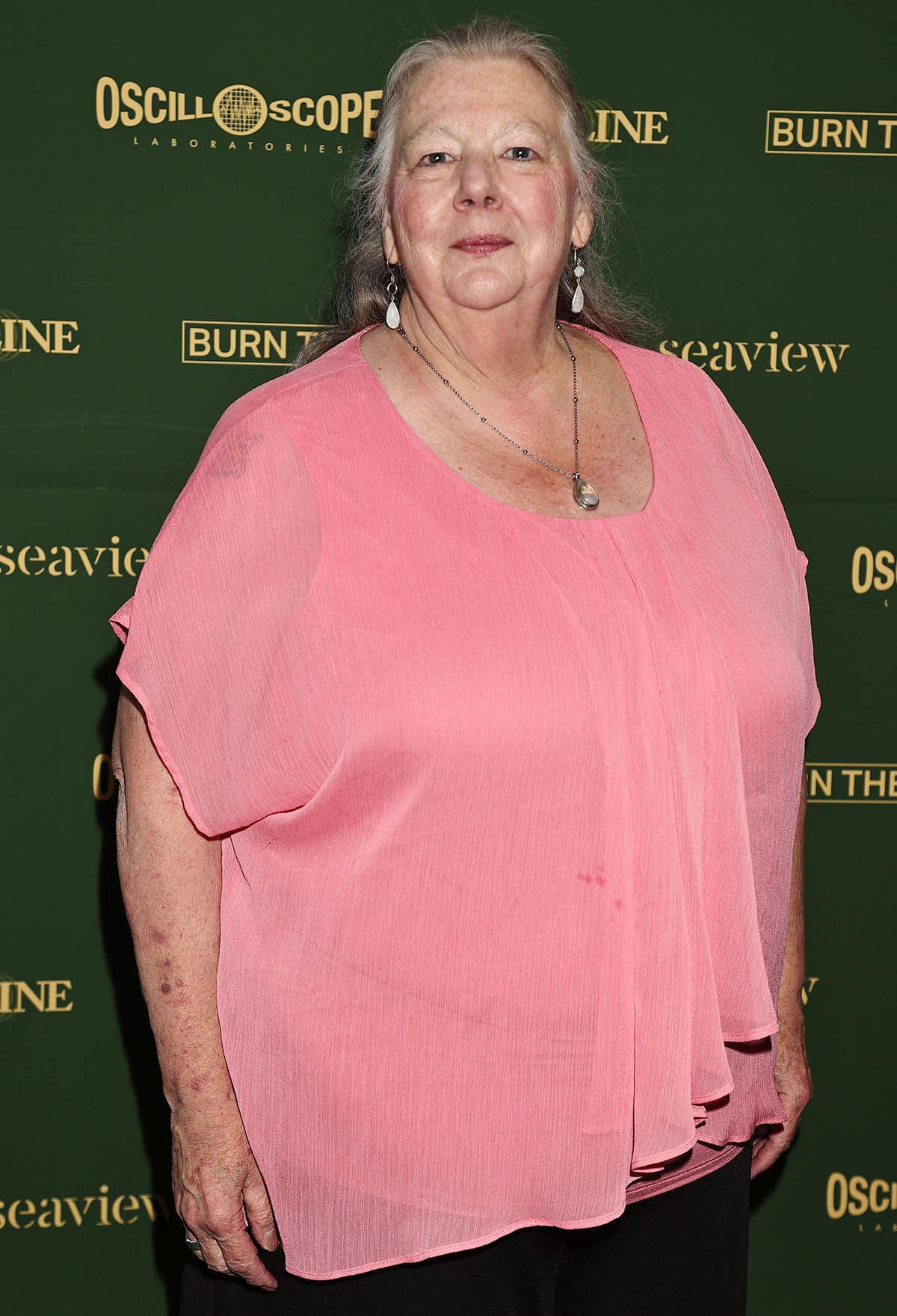Annette Deao keeps the rest of her look simple, pairing her flat sandals with wide-leg black trousers and a pink chiffon top