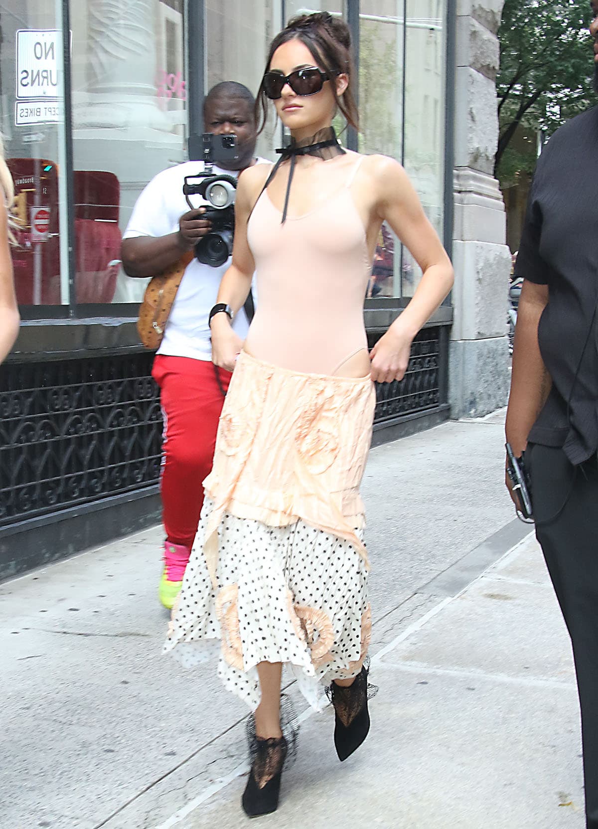 Ashtin Earle pairs her striking booties with a nude-pink bodysuit and a mixed-media midi skirt featuring a crinkled peach overlay decorated with ruffled rosettes and an asymmetrical black-and-white hem