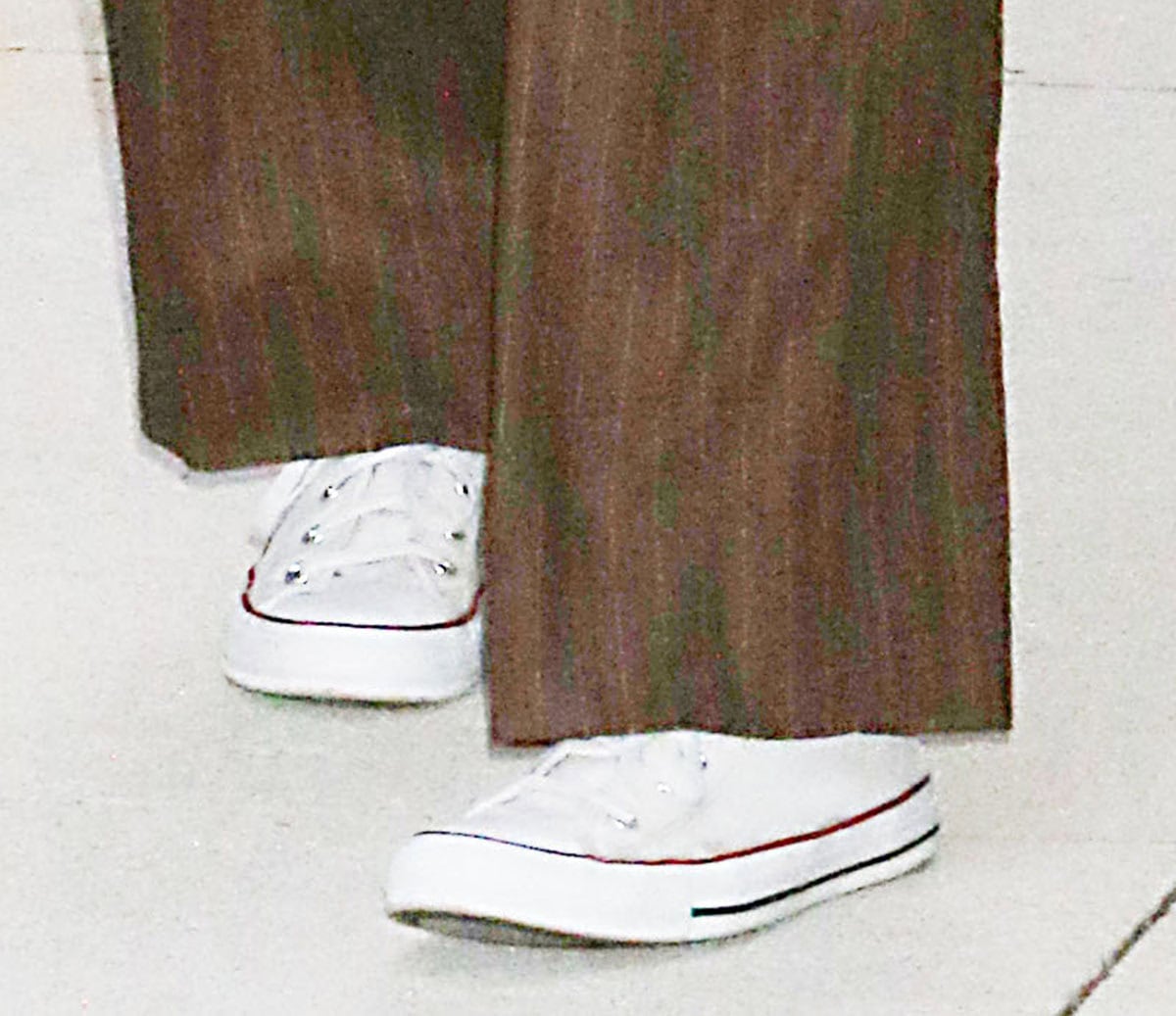 Dylan Meyer dresses down her chocolate-brown pinstriped trousers with classic white Converse Chuck Taylor All Star Low-Top sneakers, featuring canvas uppers, rubber toe caps, and signature striped midsoles