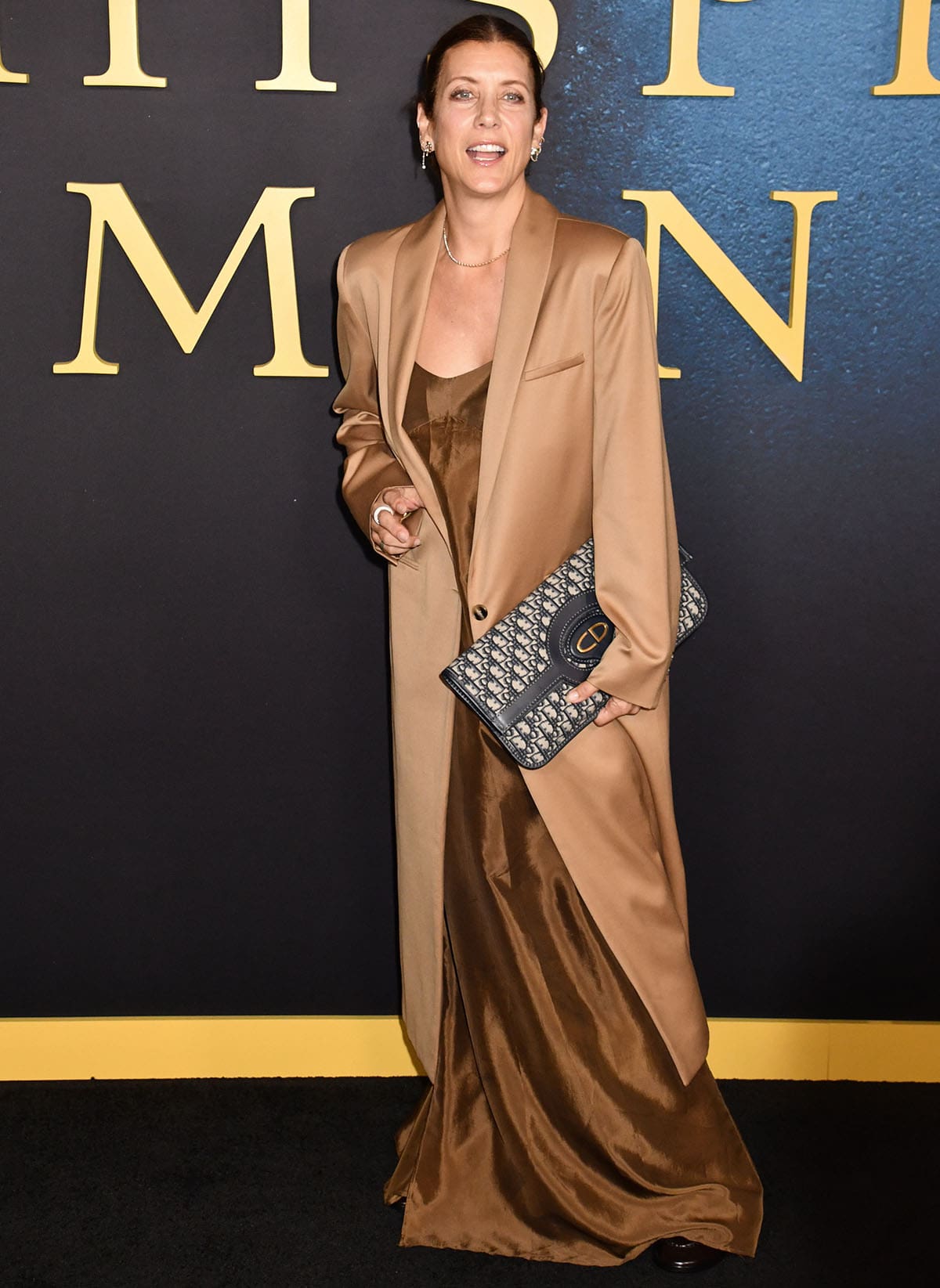 Kate Walsh looks elegant in her bronze slip-style satin dress with a long camel coat