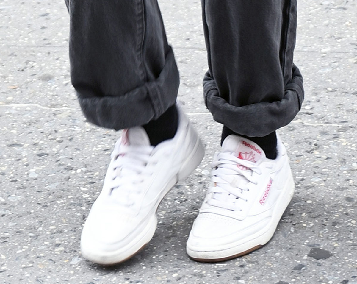 Kristen Stewart steps out in crisp white Reebok Club C 85 sneakers, their burgundy branding and gum outsole standing out beneath her cuffed charcoal jeans