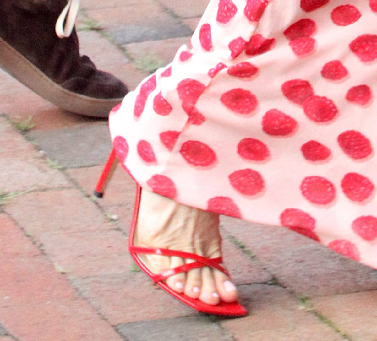 Leslie Mann slips her feet into a pair of striking red sandals with crossover front straps, square open toes, and stiletto heels