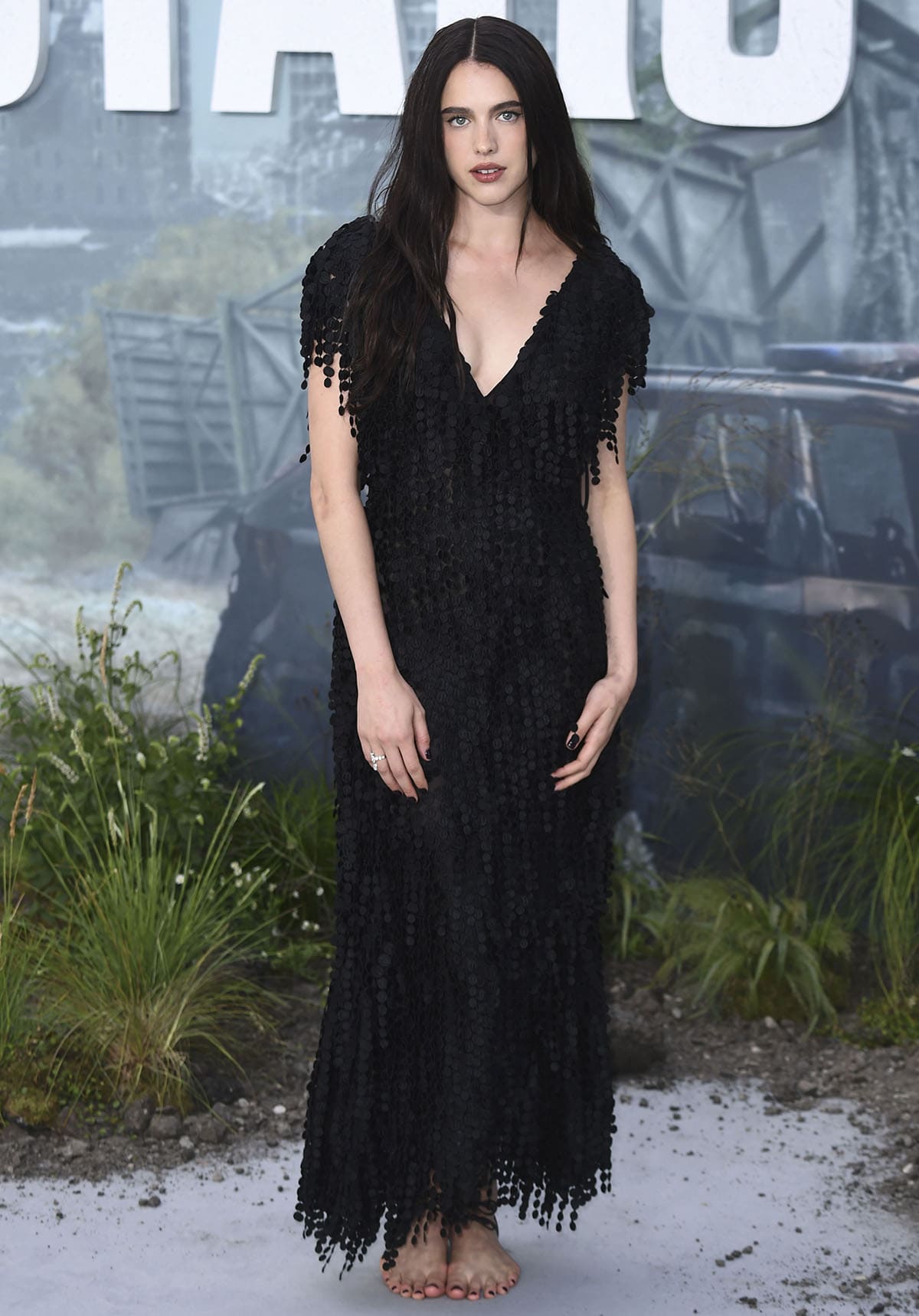 Margaret Qualley looks barefoot at the premiere, pairing her heel-cap shoes with a black Chanel Cruise 2027 dress covered in layers of tiered fringe made up of small, disc-like pieces