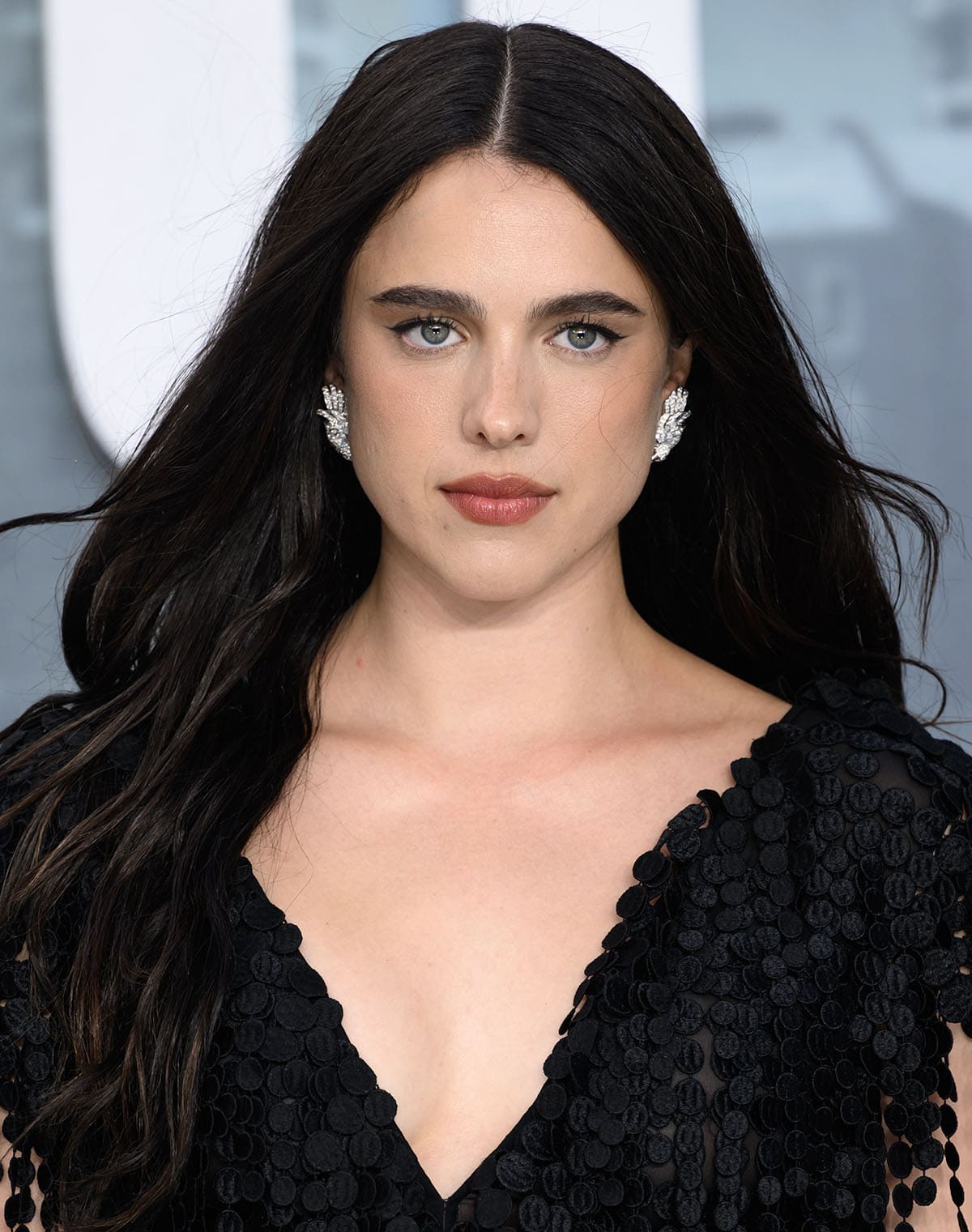 Margaret Qualley stuns with her Chanel Vol Suspendu earrings, thick eyebrows, rosy lips, and wavy raven hair