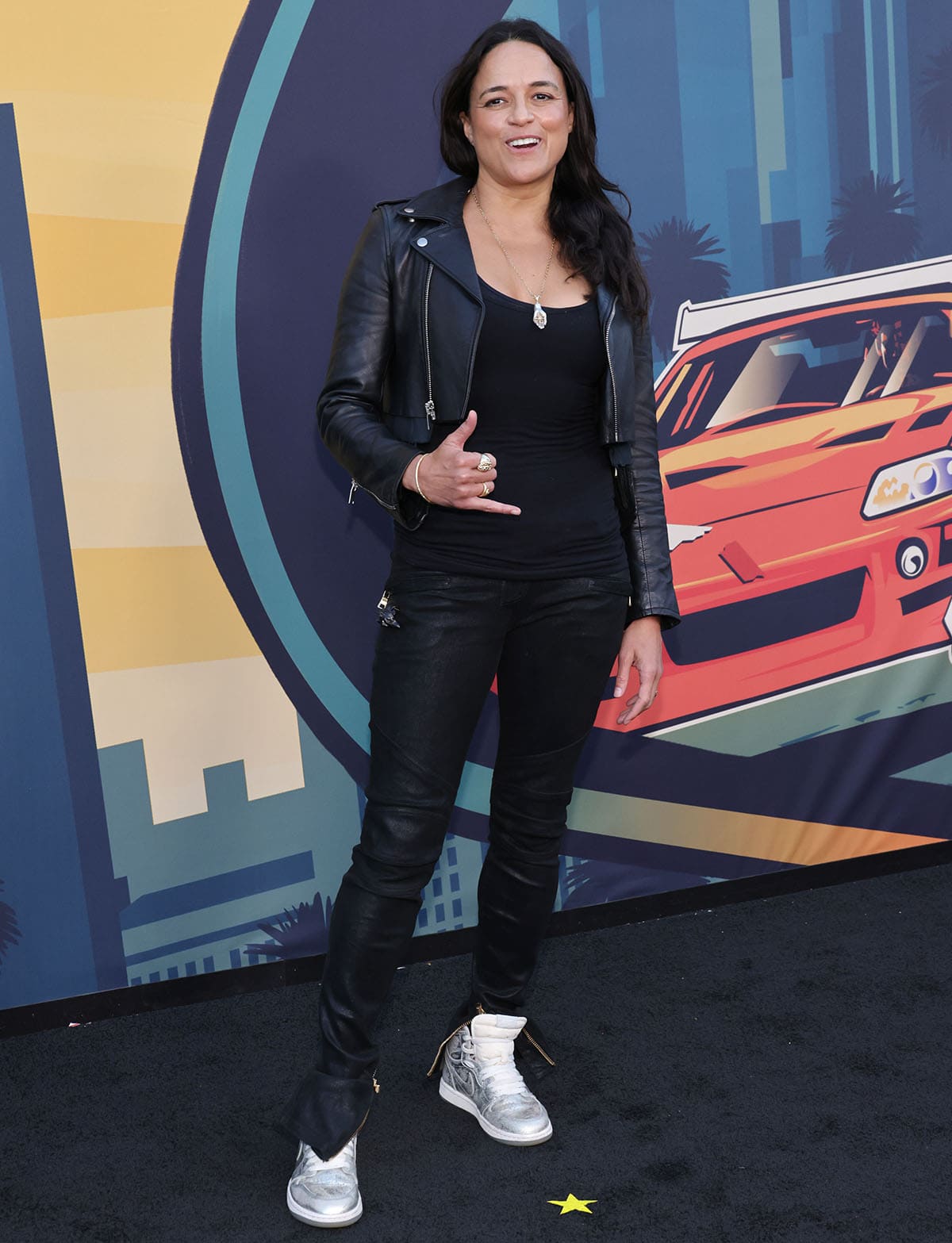 Michelle Rodriguez pairs metallic silver Air Jordan 1 High OG sneakers with an all-black biker-inspired look at The Fast The Furious 25th anniversary celebration in Los Angeles