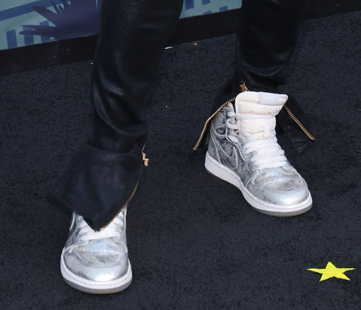 Michelle Rodriguez brings her signature tomboy style to the red carpet, wearing the Air Jordan 1 High OG sneakers in a crackled metallic silver leather with white tongues, lace-up ties, and midsoles