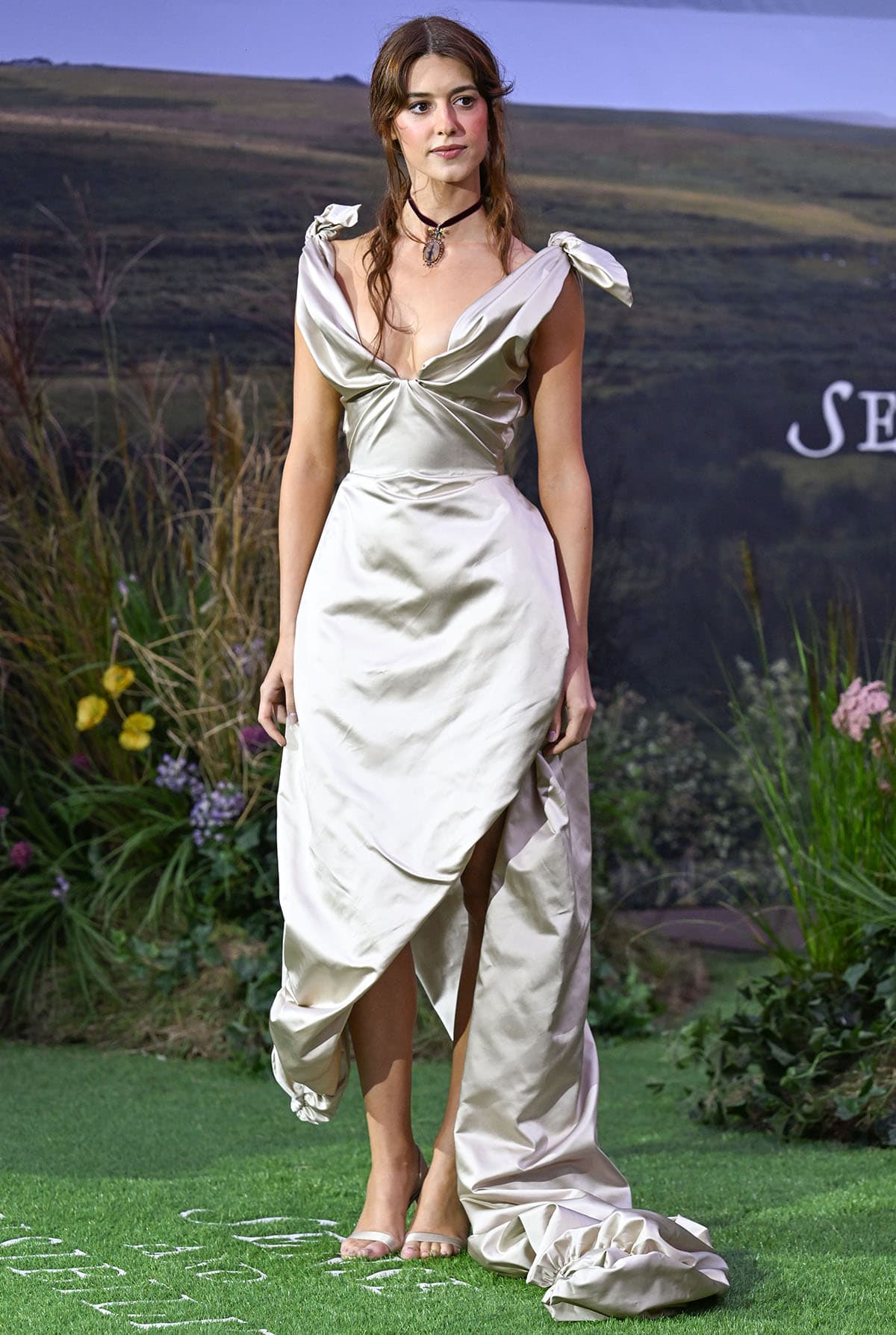 Daisy Edgar-Jones models a custom oyster satin Vivienne Westwood gown with a draped neckline, shoulder bows, thigh-high slit, and sweeping train