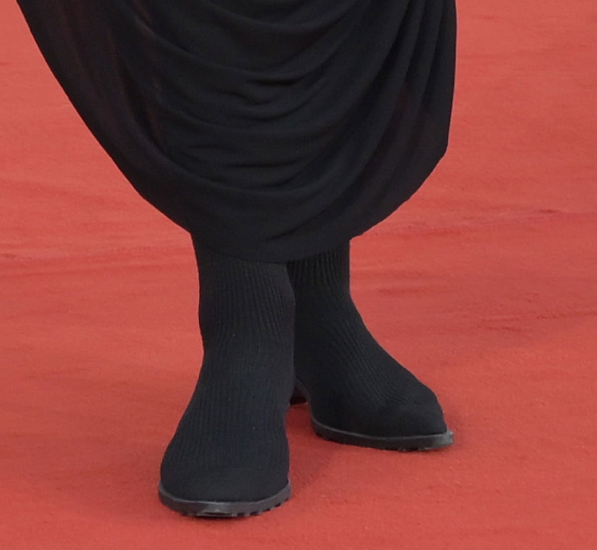 Irina Shayk wears black Camper x ISSEY MIYAKE Anna rib-knit sock boots, featuring a second-skin silhouette, sculptural pointed toes, and low architectural heels