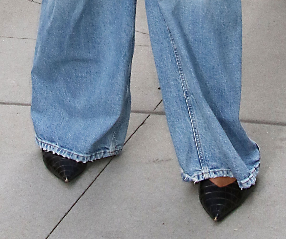 Lizzo’s glossy black croc-embossed pumps peek out beneath her wide-leg jeans, revealing sharp pointed toes and deep V-shaped vamps that visually elongate the foot