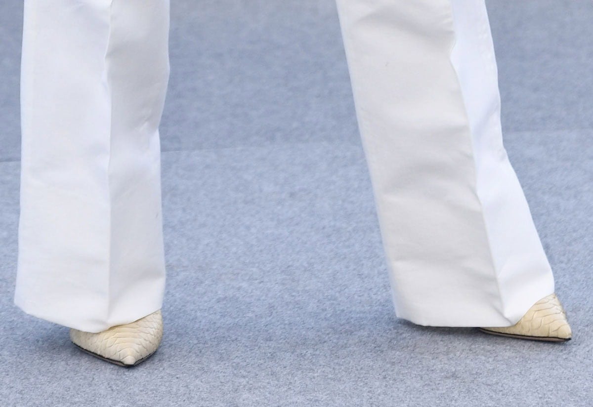 Naomi Watts wears beige python Jude Kiss pumps with pointed toes beneath white wide-leg trousers