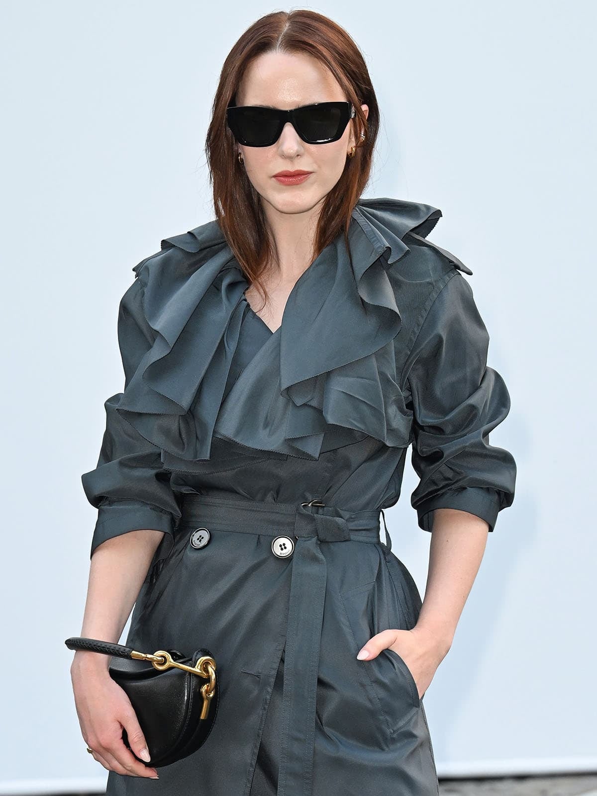 Rachel Brosnahan wears a ruffled gray Burberry trench coat and black sunglasses at the Burberry London Fashion Week show