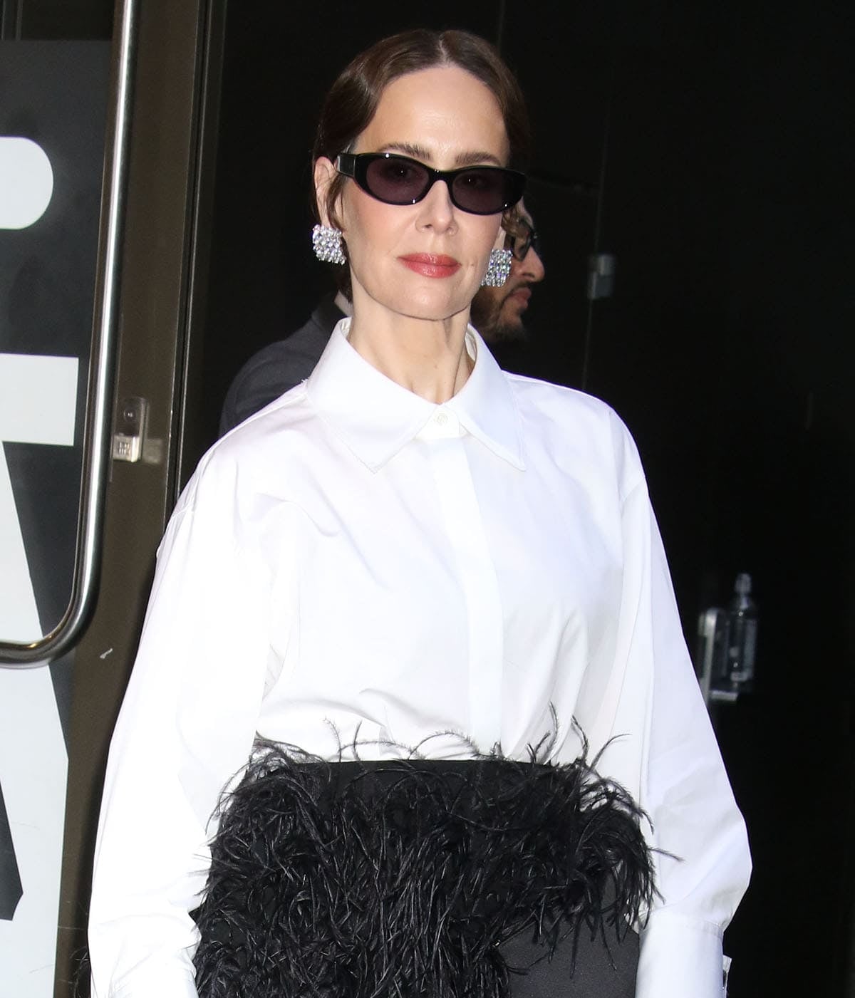 Sarah Paulson wears black sunglasses and crystal-covered Completed Works Juggernaut earrings with her hair pulled back