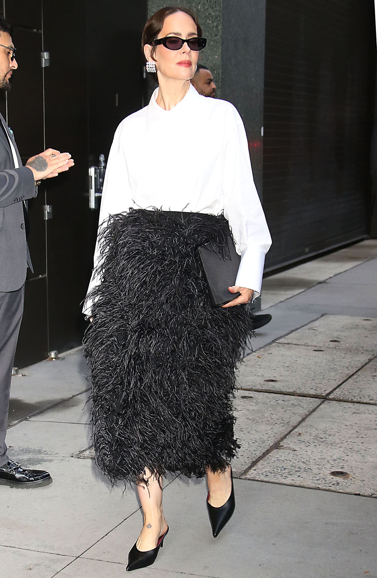Sarah Paulson wears a white Michael Kors poplin shirt with a black feather-embellished wool gabardine midi skirt and pointed mules